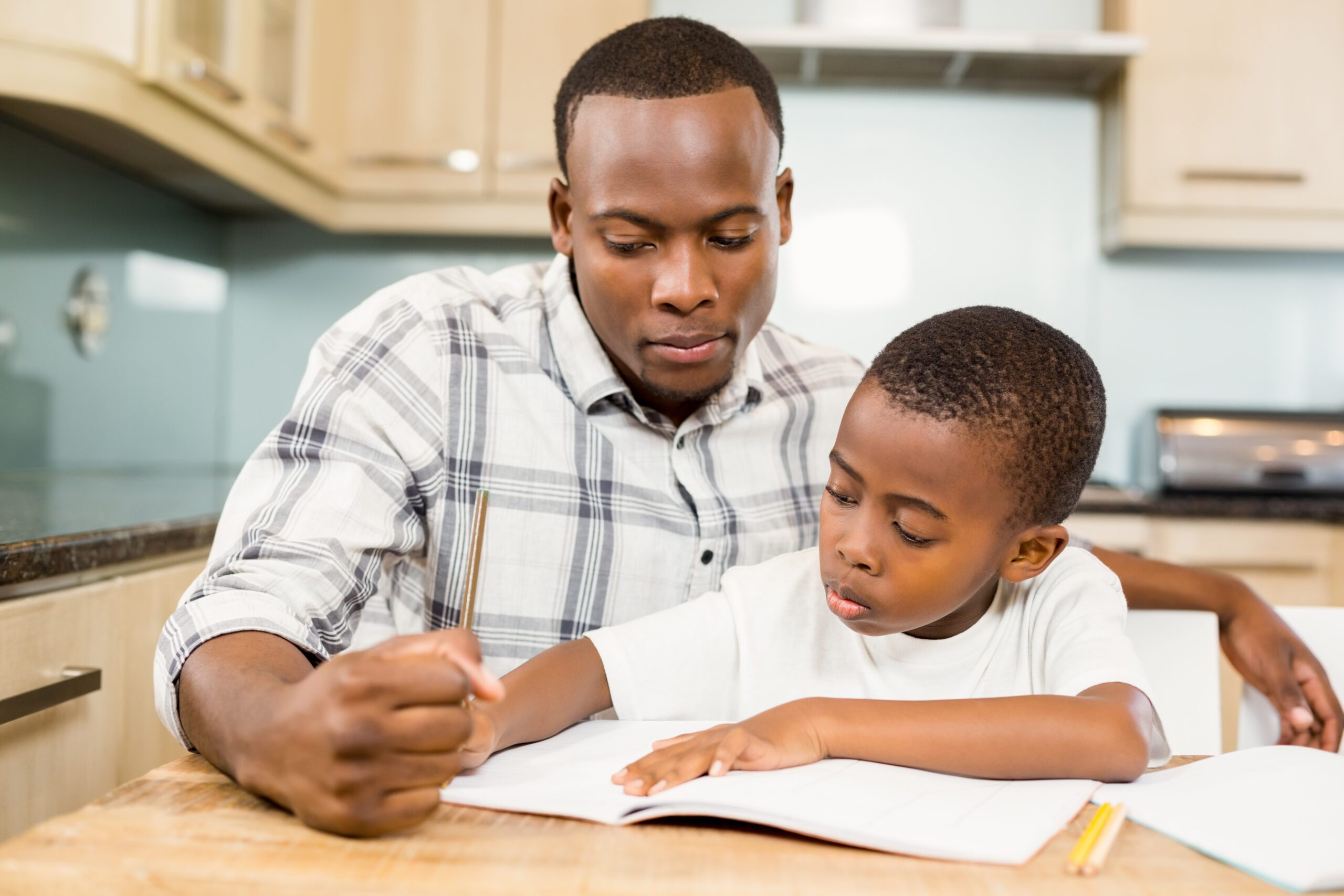 Adult helping young boy with homework in kitchen