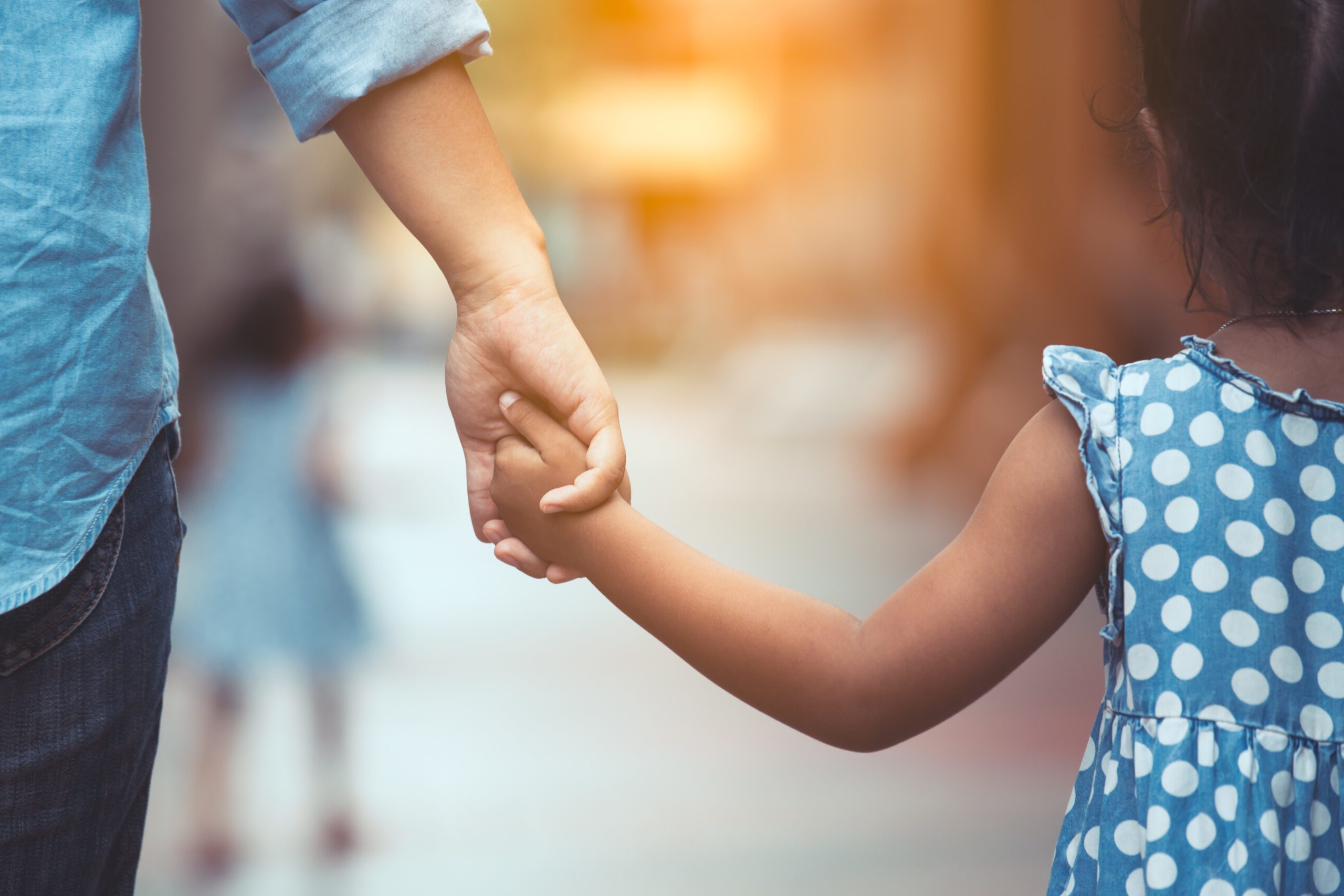 Adult and young girl holding hands