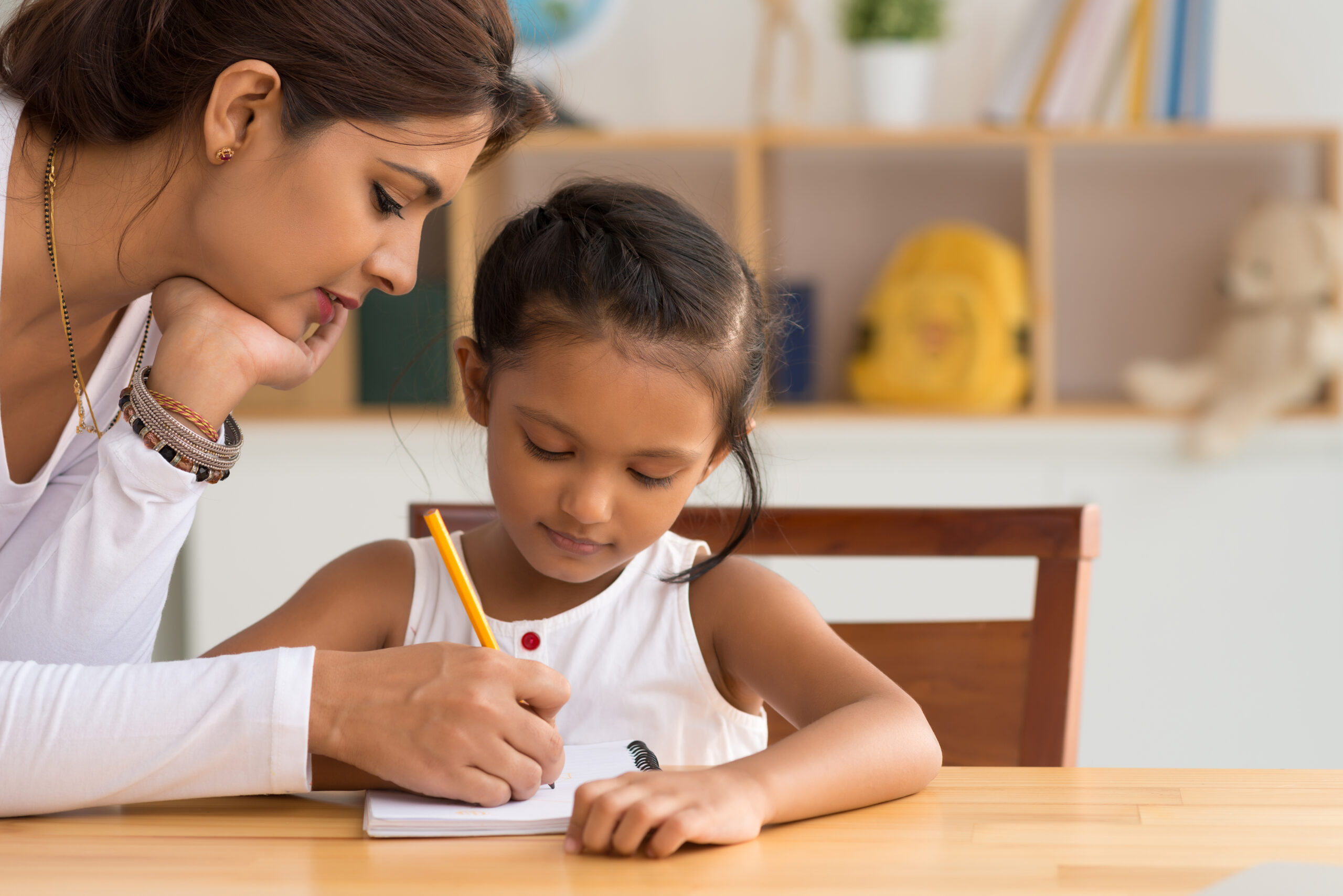 Woman helping young girl with homework