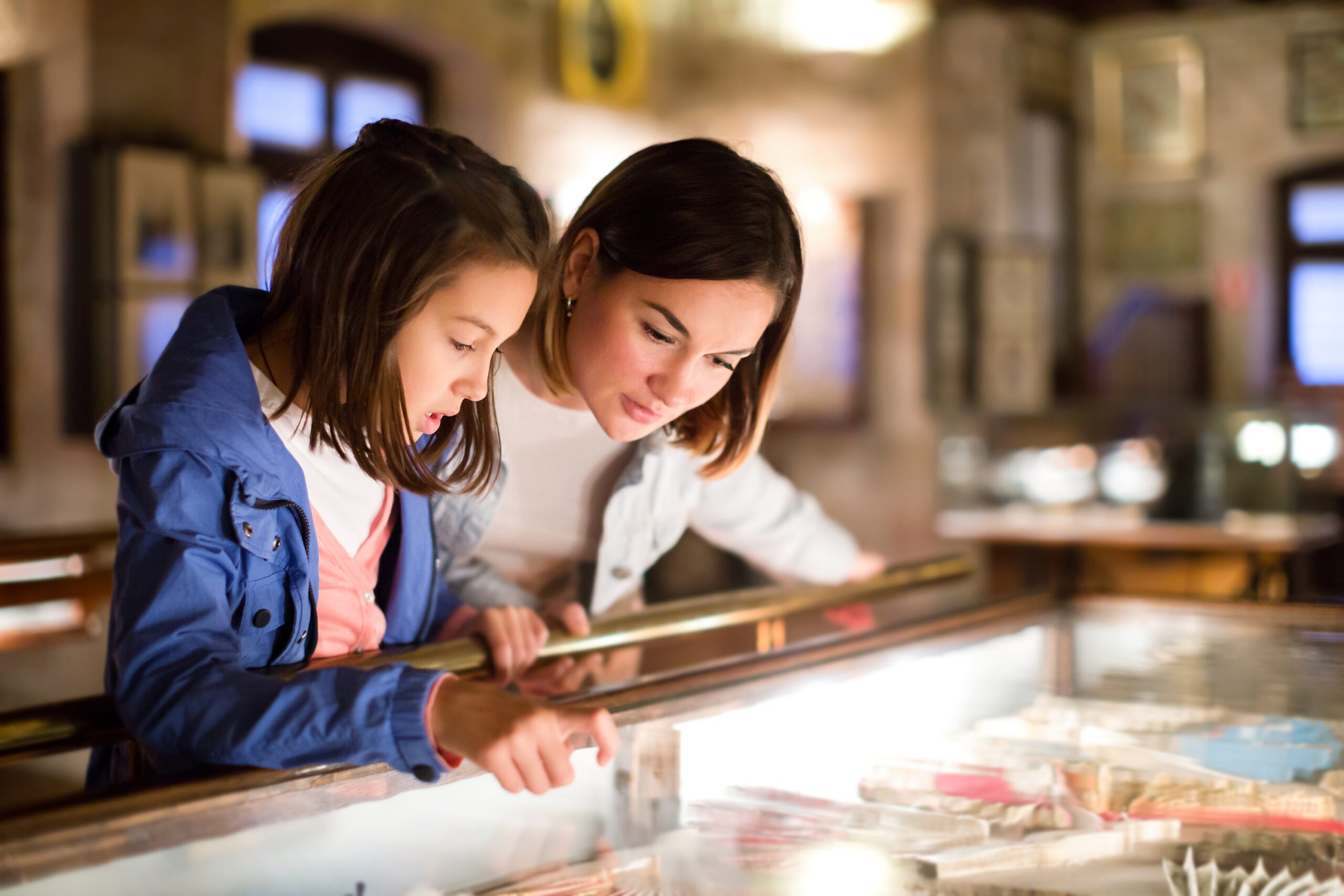 Adult and young girl exploring museum looking in display cabinet