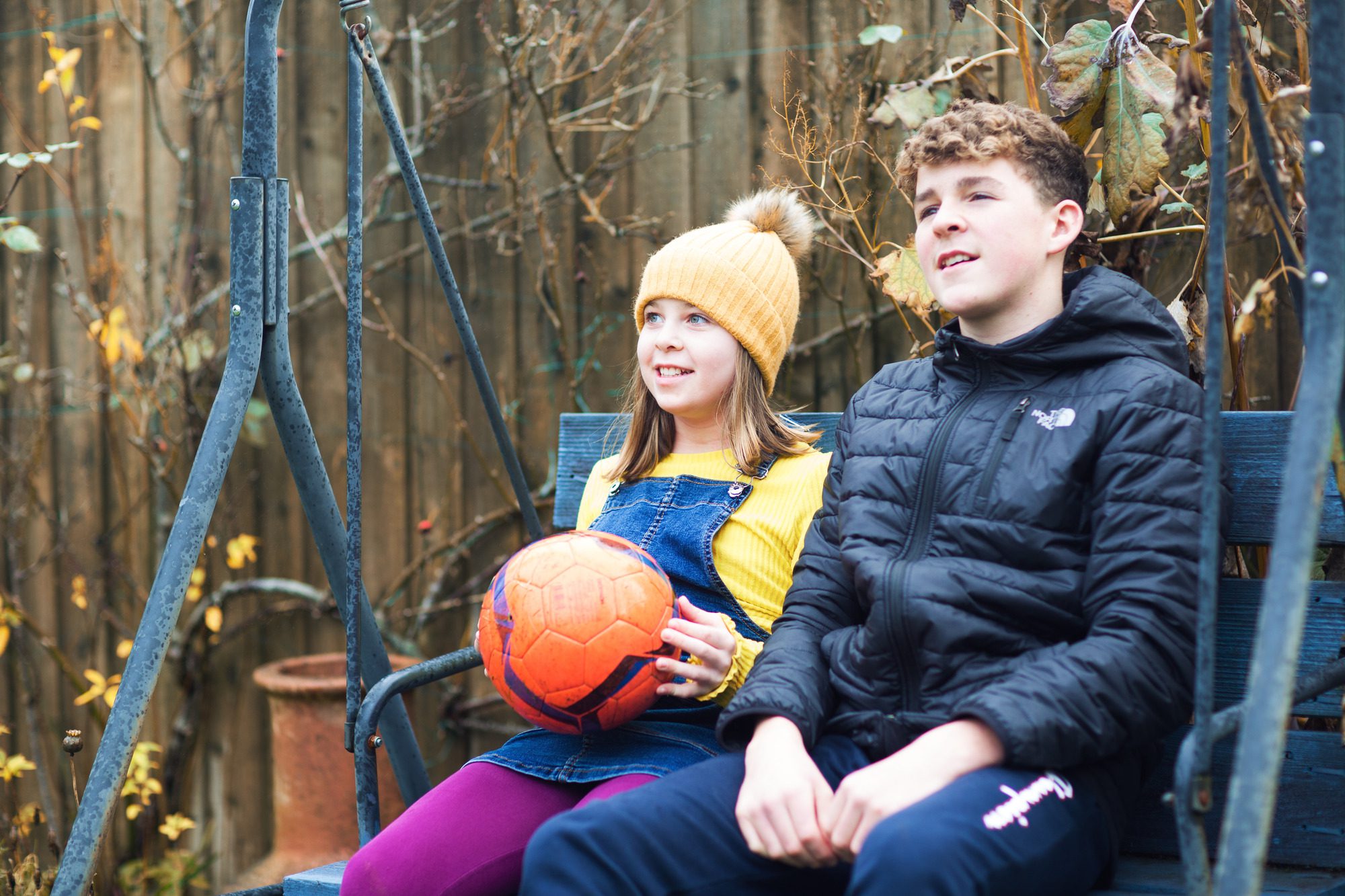 girl and boy on a garden swing with a ball